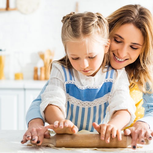 mom and daughter rolling out dough on a durable countertop in a kitchen